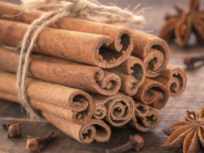 Ground cinnamon, cinnamon sticks, tied with jute rope on wooden background. Clove and star anise as