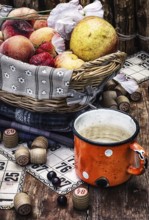 Composition of the enamel cup with water on the background fruit basket and Lotto games for picnic