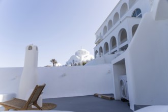 Deckchair on a viewpoint of a hotel complex, white buildings, orthodox cathedral in the background,