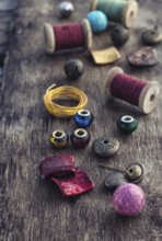 The spool of thread, beads and wire for needlework on wooden background