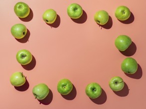 Green apples on orange or coral pink background with copy space for text or design in center,