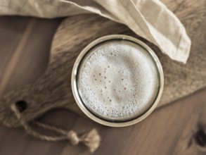 Wheat sourdough starter. Top view of glass jar with sourdough starter on wooden cutting board. Copy