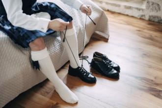 Preparing for a Scottish wedding. Man in a kilt, sporran and high socks sits on the bed and tie