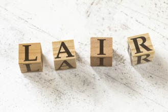 Four wooden cubes with letters LAIR (meaning Listen Acknowledge Identify Reverse) on white working