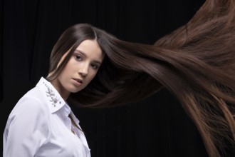 Beautiful brunette with long flying hair on a dark background