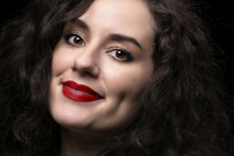 Portrait of a beautiful brunette girl with curly hair and red lipstick