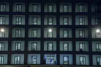 Night shot of the façade with entrance door and countless windows of the cube-shaped city library