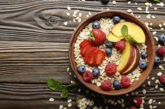 Flat lay of fruit healthy muesli with peaches strawberry almonds and blackberry in clay dish on