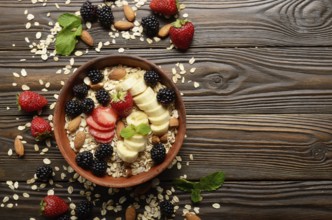 Flat lay top view at Fruit healthy muesli with banana strawberry almonds and blackberry in clay