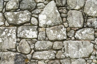 A background of an old stone wall built with uneven and random blocks and stones