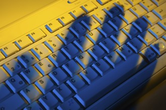 Computer keyboard and the shadow of a hand. Theft of data. Austria