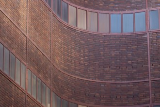 Curved brick wall section of a building with aligned windows