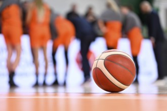 The ball lying on the parquet and the basketball team in the background.
