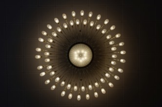 Large luxurious chandelier with burning bulbs seen from below