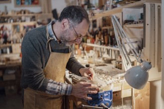 A craftsman meticulously shaping a violin part, surrounded by woodworking tools