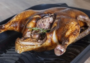 Close-up of a whole roasted or slow-baked duck in a frying pan