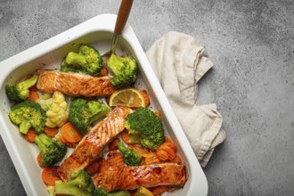 Top view of healthy baked fish salmon steaks, broccoli, cauliflower, carrot in casserole dish on