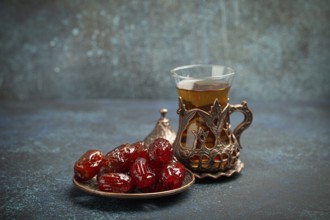Breaking fasting with dried dates during Ramadan Kareem, Iftar meal with dates and Arab tea in