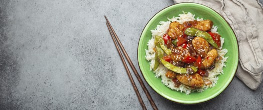 Asian sweet and sour sticky chicken with vegetables stir-fry and rice in ceramic bowl with