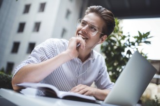 Happy handsome businessman mixes his break and job outdoors, businessman with headphones write some