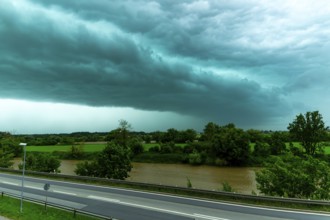 Threatening cloud formation over a road and a river in green surroundings, Bogen, Lower Bavaria