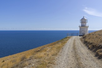 A dirt road running along a deserted mountainside to a lighthouse on the seashore. Cape Meganom,