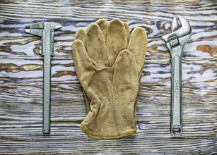 Vernier caliper adjustable spanner safety gloves on wooden board