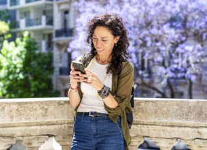 Mid-adult woman using her phone in in a bustling urban environment