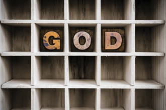 The word GOD written in vintage ink stained wooden letterpress type in a partitioned printer's