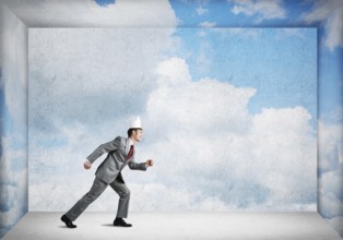 King businessman in elegant suit running in empty room with blue sky on wall