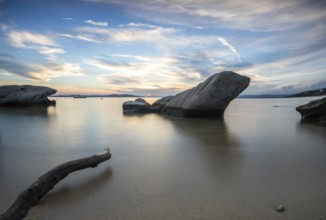 View through rocks on a sandy beach into the sunset. Landscape shot with view to the horizon over