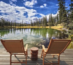 Adorable lake. Two wooden deckchairs for tourists. Coniferous forest is reflected in the mirrored
