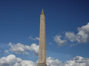 Massive obelisk in front of a clear blue sky with white clouds, Paris, France, Europe