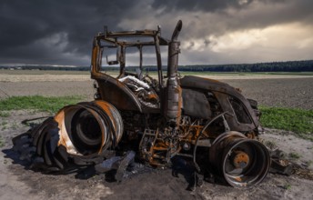 Fully destroyed burnt down tractor on a field