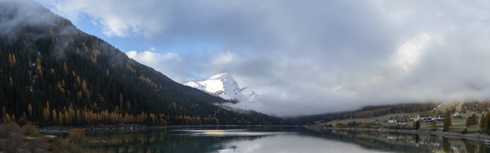 A panorama view of Lake Sufers and Pizzo Tambo and fall foliage forest reflections in the lake