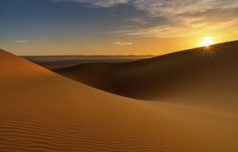A view of the sand dunes at Erg Chebbi in Morocco at sunset with a sunstar