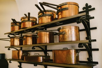 Pots, ladles, tray and saucepan made of copper, in various sizes, on massive metal shelves, fixed