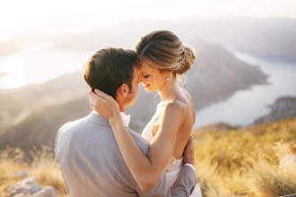 The bride and groom sitting on the top of Mount Lovcen overlooking the Bay of Kotor, smiling and