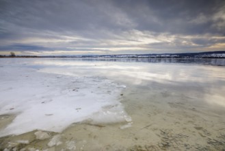 Sea of ice on the lakeshore with bright sky and snowy landscape in the background, campsite, Hegne,