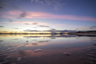 Puddle in a dune by the sea. Reflection of the sunrise in the morning. Bay and coast near