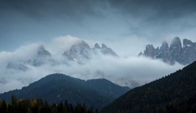 Cloudy fogy sky mountain peaks covered in mist in the morning. Dolomite rocky mountains Italy