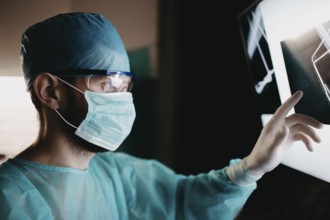 Doctor analyzing x-ray images with focused attention and protective gear