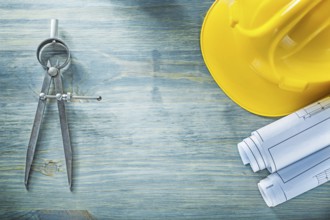 Pair of compasses blueprints hard hat on wooden board construction concept