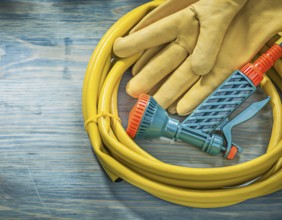 Leather protective gloves garden hose on wooden board gardening concept