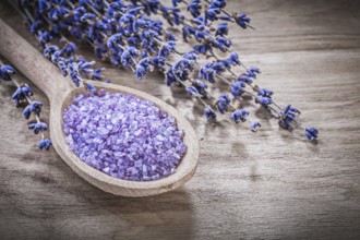 Dried scented curative lavender sea salt wooden spoon on wood board spa treatment concept