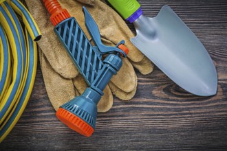 Coiled garden rubber hose protective gloves hand shovel on wood board gardening concept