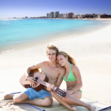 Blond young tourist couple playing guitar at beach in Mexico Caribbean photo mount