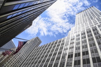 Low angle view of American flag and skyscrapers against sky in New York City. Finance, business and