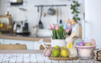 Easter decoration of colorful eggs in a basket and a rabbit on the kitchen table in a rustic style.