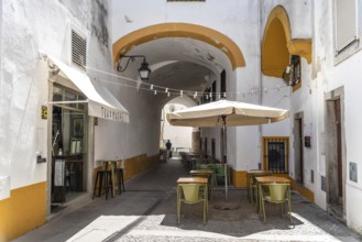 Evora, Portugal, June 30, 2022: Narrow street in the old town with restaurant terraces. Alentejo,